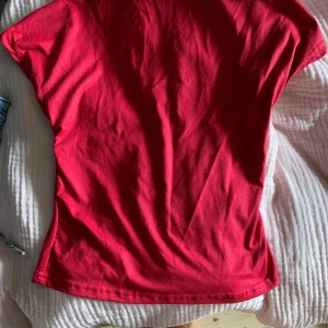 Röd topp med öppen rygg - Säljer en röd topp med öppen rygg. Toppen har korta ärmar och öppen rygg. Perfekt att styla med jeans eller kjol för en trendig vibe.