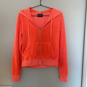 Juicy Couture orange/coral velour hoodie - Oanvänd superfin Juicy Couture hoodie i storlek Small i orange/coral velour med dragkedja och huva. Klassisk Juicy-logga broderad på bröstet och snygg J-detalj på dragkedjan.Perfekt för en chill och trendig look. 