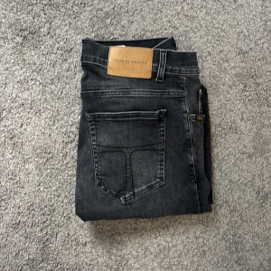 Svarta jeans från Tiger of Sweden - Snygga svarta jeans från Tiger of Sweden med klassisk femficksdesign och diskret tvättad look. Jeansen har normal passform, bälteshällor och knappgylf. Perfekta för dig som gillar stilrena och tidlösa plagg.