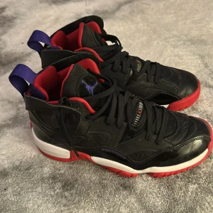 Nike Air Jordan sneakers svart/röd - Snygga Nike Air Jordan sneakers i svart skinn med röda och vita detaljer samt lila dragflik bak. Skorna har klassisk snörning, röd insida och den ikoniska Jumpman-loggan på hälen. Perfekta för dig som gillar streetstyle och vill sticka ut.