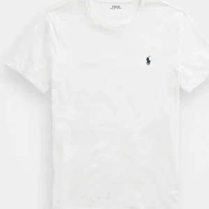 Vit t-shirt från Polo Ralph Lauren - Klassisk vit t-shirt från Polo Ralph Lauren med broderad marinblå logga på bröstet. T-shirten har rund hals, korta ärmar och är gjord i mjuk bomull. Perfekt basic-plagg med snygg passform och stilren look.