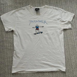 Vit Thrasher t-shirt  - Vit t-shirt från Thrasher med ett unikt tryck av en tecknad figur