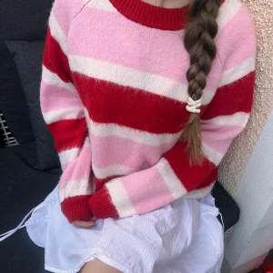 Randig stickad tröja från Pieces - Supermysig stickad tröja från Pieces med breda ränder i rött, rosa och vitt💗Jag är 167cm och brukar ha S. Denna är i L så blir mer oversize på mig vilket jag gillar. 