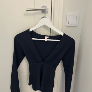 Svart omlottopp från Holly & White - Supersnygg svart omlottopp från Holly & White med djup v-ringning och korta puffärmar. Den är i storlek S men känns som xs🥰