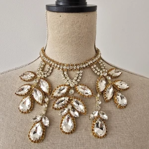 Statement halsband med stora kristaller - Superglammigt statement halsband med stora, klara kristaller i dropp- och marquiseform. Kristallerna är infattade i guldtonad metall och halsbandet har en lyxig, glittrig känsla. Perfekt för dig som vill sticka ut och glänsa extra mycket.