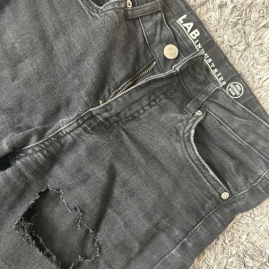 Svarta jeans med hål från LAB Industries - Säljer ett par svarta jeans från Kappahl med slitningar. Har själv klippt hålen🙌Tvättar alltid innan köp! D där i strl 152 men jag har runt 164 och kan ha på mig de så är väldigt stretchiga.☺️Använda men inga slitningar förutom hålen.