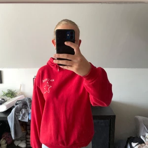 Röd hoodie från Gina Tricot med stjärna - Röd hoodie från Gina Tricot med vit stjärna och texten 'MA CHÉRIE' tryckt både fram och bak. Tröjan har huva, långa ärmar och ribbade muddar. Perfekt för dig som gillar en chill och snygg stil.
