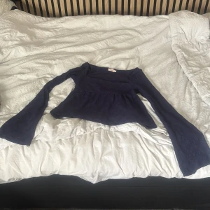Mörkblå spetsblus från Nelly - Supersnygg mörkblå blus från Nelly med vida långa ärmar och vacker spetsstruktur. Toppen har en lätt utställd passform nedtill och markerad midja. Perfekt för dig som vill sticka ut med en unik och trendig look. Aldrig använd