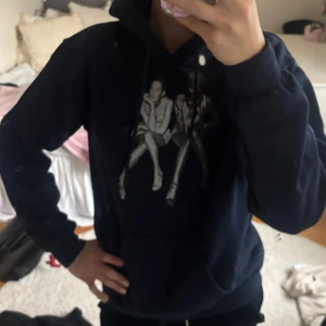 In print we trust hoodie - Cool mörkblå med ett stort grafiskt tryck av två personer på framsidan. Tröjan har huva med snörning och en klassisk känguruficka. Perfekt för dig som gillar streetstyle och vill sticka ut lite extra. Jättesnygg och knappt använd!