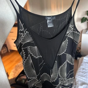 Svart mönstrad topp Filippa K - Svart topp från Filippa K med tunna axelband och  snyggt mönster. Något genomskinligt material. 