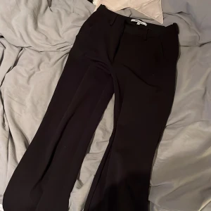 Svarta kostymbyxor från ONLY XS - Snygga svarta kostymbyxor från ONLY tailoring i storlek XS/32. Byxorna har klassisk rak passform med vida ben och hällor för bälte. Perfekta för en clean och stilren look. Materialet är mjukt och följsamt.