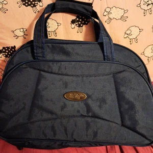 Blå väska från Mr. Bag - Stor och rymlig blå väska från Mr. Bag med mjuk form och dubbla handtag. Väskan har ett stort huvudfack, innerfickor och dragkedja. Tillverkad i slitstark polyester och perfekt för dig som behöver mycket plats. Den är helt ny och oanvänd, och har en rem som man kan sätta på för att hänga kring axeln :)