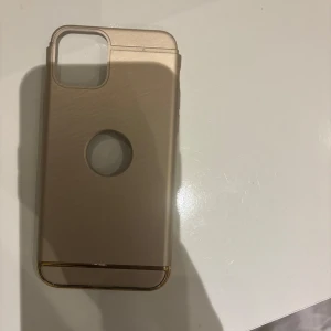 Guldig mobilskal till iPhone 11 Pro - Snyggt guldig mobilskal till iPhone 11 Pro med stilren design och rund öppning på baksidan. Skalet har en metallik känsla och detaljer i guld längst ner. Perfekt för dig som vill ge mobilen en lyxig touch.