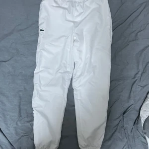 Vita sportbyxor från Lacoste small - Säljer ett par vita sportbyxor från Lacoste med elastisk midja och avslappnad passform. Byxorna är bra inför sommar sköna. Kvalité 10/10 inte använd. Small/medium