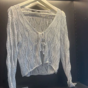 Silver glittrig kofta från Bik Bok - Säljer en snygg silverfärgad glittrig kofta från Bik Bok. Den har en v-ringad design med knyt framtill och långa ärmar. Perfekt för att lägga till lite glitter i din outfit! ✨