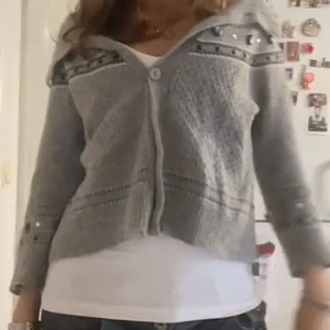 Grå kofta med knappar - Säljer en mysig grå kofta med knappar framtill. Koftan har stenar och mönster längst ner på armarna och upptill och trekvartsärmar💕