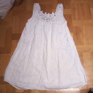 Vit klänning från Vero Moda - Säljer en söt vit klänning från Vero Moda med vackra spetsdetaljer vid axelbanden och halsringningen. Klänningen är ärmlös och har en luftig passform, perfekt för varma dagar. Den är gjord i ett lätt och bekvämt material.