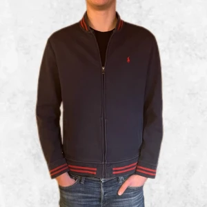 Marinblå full zip från Ralph Lauren - Säljer en stilren mörkblå full zip från Ralph Lauren med den klassiska röda loggan på bröstet. Den är i väldigt bra skick (9/10). Storlek M men kan även passa en större S. Vid några frågor eller funderingar är det bara att höra av sig. 
