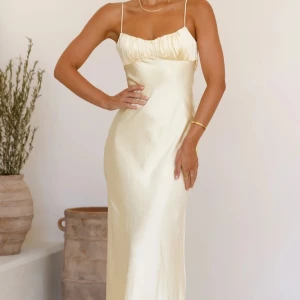 Ljusgul bal/ långklänning i satin med öppen rygg - Ljusgul långklänning i satin med smala axelband och öppen rygg. Klänningen är ifrån Billy J och är aldrig använd. Den är i storlek 6 vilket motsvarar 34, skulle säga att den är normal i storlek. Som referens så har jag normalt storlek 32 och är 160 cm lång. 