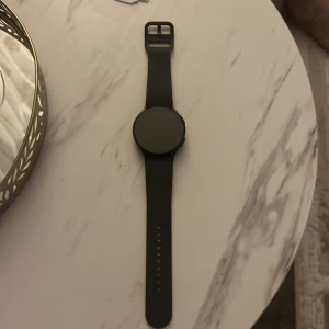 Svart smartklocka med digital urtavla - Snygg och modern svart smartklocka med rund digital urtavla. Klockan har en stilren design med en tydlig display och justerbart armband. Perfekt för den teknikintresserade!