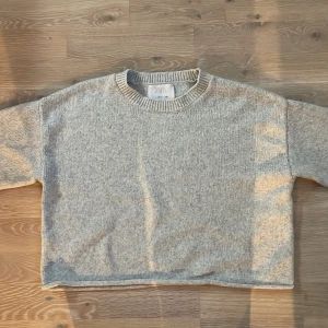 Grå stickad tröja från Zara - Säljer en mysig grå stickad tröja från Zara. Tröjan har en ljusgrå nyans och är även lite kortare. Perfekt för kyligare dagar! Säljer eftersom att jag själv har växt ur den!! 💞💞