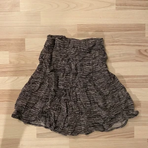 Mönstrad kjol från Indiska - Säljer en snygg mönstrad kjol från Indiska. Kjolen har ett svart och vitt mönster och är i en luftig modell. Perfekt för en stilren look.