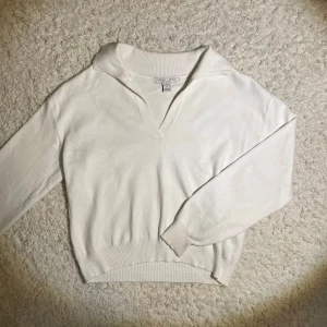 Vit tröja från Amisu - Säljer en stilren vit tröja från Amisu med en v-ringad krage. Tröjan har långa ärmar och ribbade muddar vid ärmslut och nederkant. Perfekt för en avslappnad look.