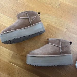 Uggs ultra mini platform  - Uggs ultra mini plattform I chestnut. Storlek 37. Använda men i bra skick. Skorna är lite slitna där fram (se bilder) och har vissa täcken på användning. Men inget man ser tydligt enligt mig. Jag har lagt till hälskydd för att göra skorna mer bekväma men det går att ta bort.  
