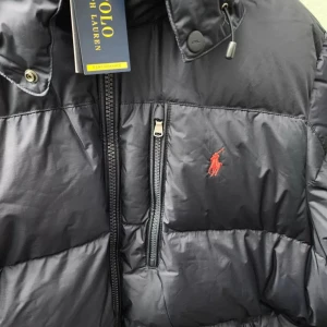 Svart dunjacka från Polo Ralph Lauren - Om du har några frågor så tveka inte på att skriva. Säljer en snygg svart dunjacka från Polo Ralph Lauren med röd logga på bröstet. Jackan har en dragkedja framtill och en praktisk bröstficka med dragkedja. Perfekt för kyliga dagar! Säljer pga att jag inte har någon användning av den nu i sommar köpte den i början av vintern på ascot i Gävle.