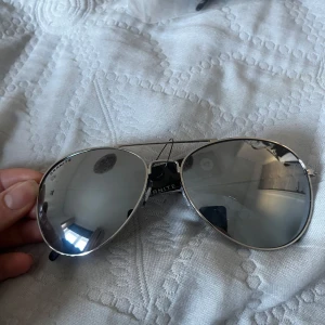   Silvriga pilotglasögon från Granite Eyewaer - Snygga solglasögon i klassisk pilotstil från Polaroid. De har en silverfärgad metallram och spegelglas som ger en cool look. Perfekta för soliga dagar och ger ett stilrent intryck.