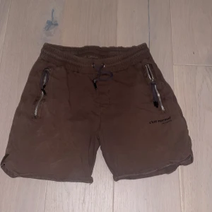 Bruna shorts från C'est Normal - Snygga bruna shorts från C'est Normal med dragkedjor på sidorna och snörning i midjan. Perfekta för en avslappnad stil.