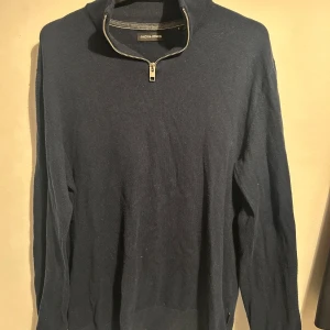 Jack and Jones tröja - Snygg mörkblå tröja från Jack & Jones med dragkedja vid halsen. Perfekt för kyligare dagar med sin långa ärmar och bekväma passform. En stilren och mångsidig tröja för alla tillfällen. Storlek S