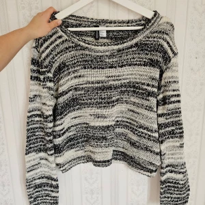 Svartvit randig stickad tröja från H&M - Säljer en mysig svartvit randig stickad tröja från H&M. Tröjan har en rund halsringning och långa ärmar, perfekt för kyligare dagar. Den är både stilren och bekväm, ett måste i garderoben!🩷