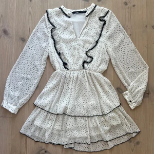 Vit prickig klänning från Zara - Säljer den här jätte söta vit klänning från Zara med svarta prickar och volangdetaljer❤️Klänningen har långa ärmar och en v-ringad design❤️Säljer eftersom den tyvärr är för liten för mig och använd endast 1 gång❤️
