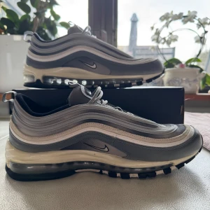 Nike Air Max 97 Cool grey - Säljer ett par stilrena Nike Air Max 97 i grå och vit. Skorna har en ikonisk vågig design med synlig Air-enhet i sulan för extra komfort. Perfekta för både vardag och träning. Enbart använda ett fåtal ggr, nästintill oanvända. Nypris ca 2300 kr. 