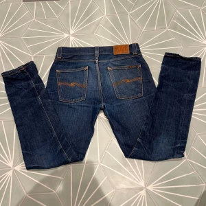 Mörkblå jeans från Nudie Jeans - Säljer nu dessa snygga mörkblå jeans från Nudie Jeans med klassisk femficksdesign och orange sömmar. Modellen heter lean dean. Inga defekter. Skriv om du har en fundering!🤙