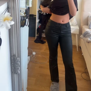 Svarta bootcut byxor - Snygga svarta bootcut byxor med hög midja. Byxorna har en stilren design och är perfekta för en trendig look. De är tillverkade i ett material som ger en skinnliknande finish.