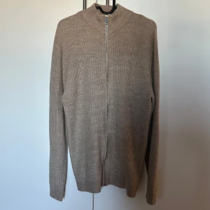 Beige stickad ull kofta full zip - Säljer en stilren beige stickad kofta med dragkedja. Perfekt för våren. Snygg i nyskick 10/10.