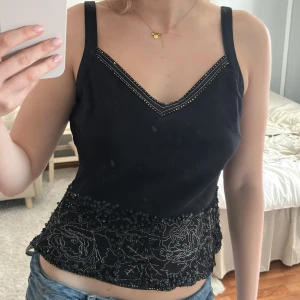 Svart linne med spetsdetaljer - Snygg svart linne med v-ringning och spetsdetaljer längst ner. Superfin och passar en s/m