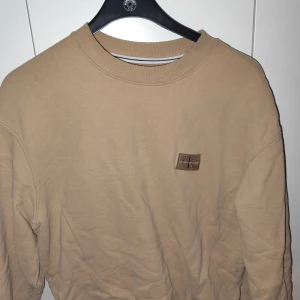 Beige tröja från Calvin Klein Jeans - Säljer en stilren beige tröja från Calvin Klein Jeans. Tröjan har en rund halsringning och en diskret logga på bröstet. Perfekt för en avslappnad look.