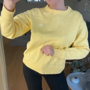 Gul sweatshirt från Acne Studios - Säljer en gul sweatshirt från Acne Studios med en liten fyrkantig logga på bröstet. Tröjan har en rund halsringning och långa ärmar. 