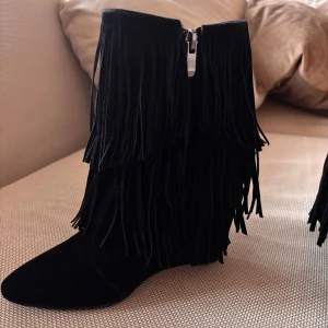 Svarta boots med fransar - Snygga svarta boots med fransar och kilklack. De har en spetsig tå och dragkedja på sidan. Inte smutsiga bara lite damm