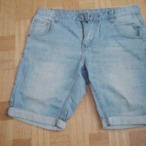 Ljusblå jeansshorts - Säljer ett par ljusblå jeansshorts från WA. De har en klassisk femficksdesign och är uppvikta vid bensluten. Perfekta för en avslappnad stil.