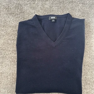 Marin blå v-ringad tröja från Uniqlo - Säljer en stilren marin blå  v-ringad tröja från Uniqlo. Tröjan är i nyskick och är sparsamt använd. Material 100% merinoull. Nypris 500 mitt pris 249. Skriv vid frågor.