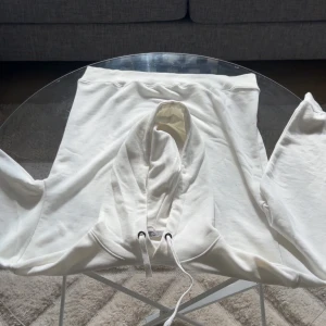 Vit hoodie från Alexander McQueen - Säljer en stilren vit hoodie från Alexander McQueen med svart tryck framtill. Svagt andvänd utan defekter en sliten påse medföljer och tags.