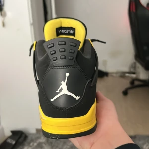 Svarta och gula Nike Air Jordans - Snygga Nike Air Jordans i svart och gult med ikonisk Jumpman-logga på hälen. Skorna har ett nätmönster på sidorna och snörning framtill. Perfekta för dig som vill ha en stilren och sportig look. 