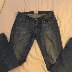Blå jeans från Acne Studios - Snygga blå jeans från Acne Studios med klassisk femficksdesign och knappgylf. Perfekta för en stilren look. De har en normal passform och är tillverkade i stretchigt denim för extra komfort. Hör av er vid frågor o funderingar!