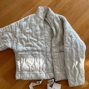 Quiltad beige jacka med dragkedja - Quiltad jacka från Zara i ljusbeige med vågigt mönster, hög krage och dragkedja framtill. Kom privat för flera bilder