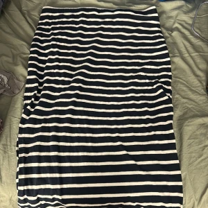 Randig långkjol från Lindex - Säljer en snygg långkjol från Lindex i marinblått och vitt med horisontella ränder. Kjolen har en rak passform och är gjord i mjuk bomull, perfekt för en chill och stilren look. Elastisk midja för extra komfort.