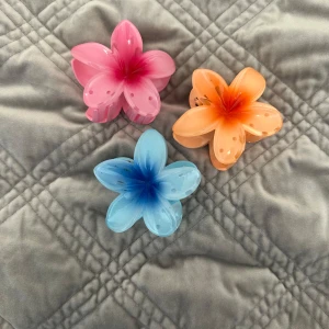 Färgglada blommiga hårklämmor - Tre stora hårklämmor i form av blommor i rosa, orange och blått. Klämmorna har en cool färgskiftning från mitten och små prickiga detaljer på bladen. Perfekt accessoar för att piffa upp frisyren med en lekfull touch.